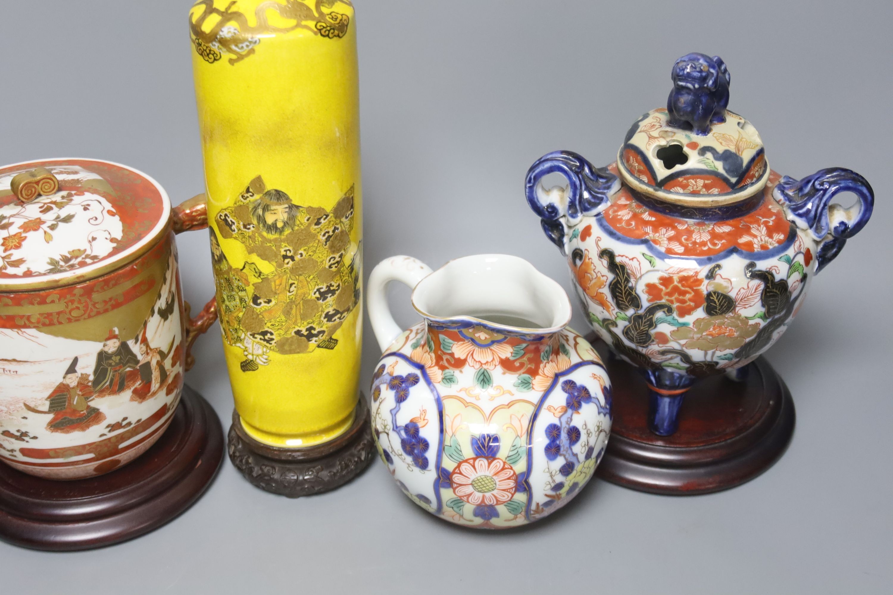 A Satsuma yellow ground vase, a Kutani twin handled cup and cover, a Fukugawa Imari jug and an Imari koro and cover 27cm, three wood stands